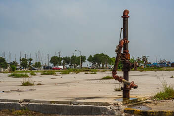 Post-hurricane image of piping covered in rust in an empty landscape with trees in the far background